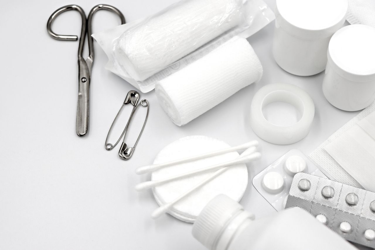 Home A detailed flat lay of essential first aid supplies including bandages, scissors, and pills.