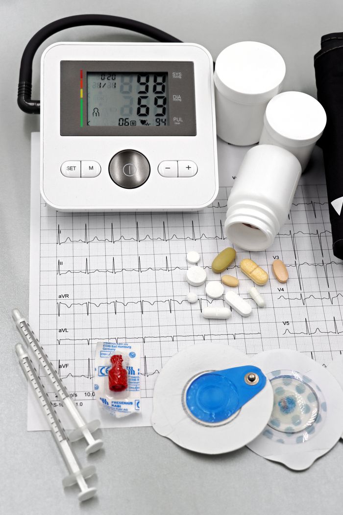 Home Medical setup featuring blood pressure monitor, pills, syringes, and ECG printout for healthcare themes.