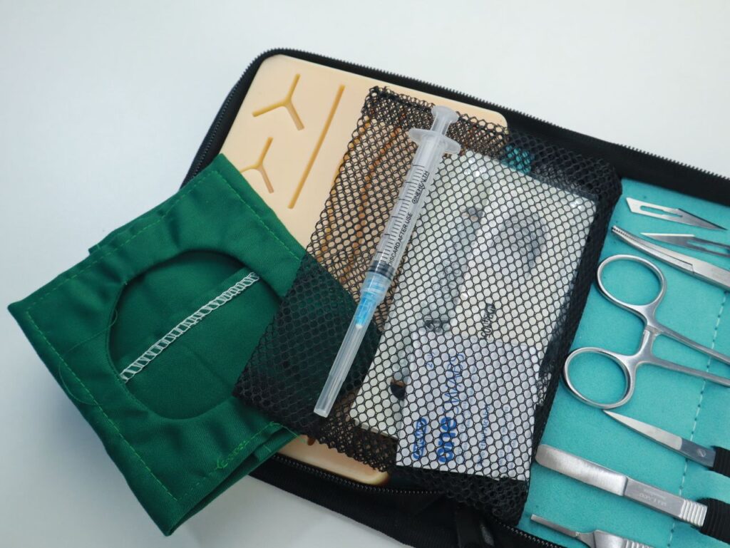 Close-up of a medical training kit featuring surgical tools and a syringe.