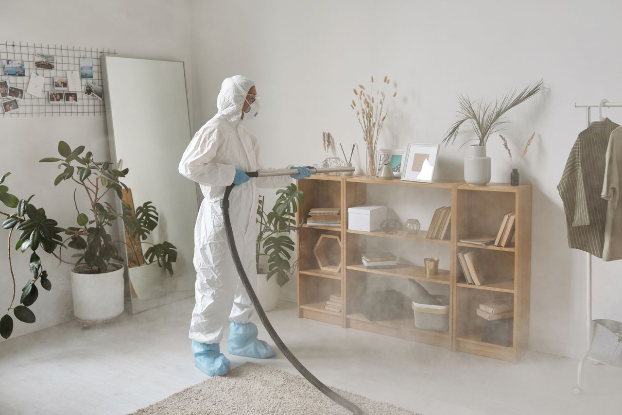 About Person in protective suit disinfecting indoor space with fumigation equipment.